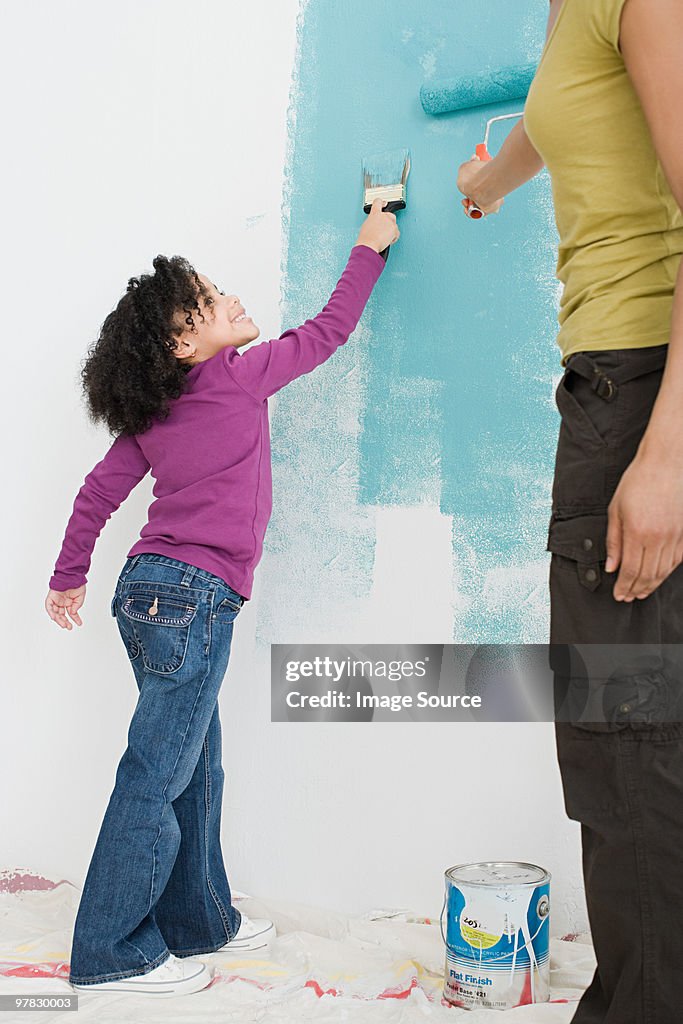 Girl and mother painting a wall