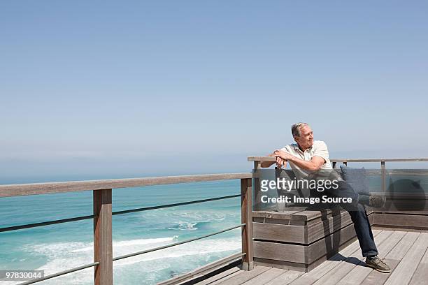 senior man on balcony by the sea - beach house balcony stock pictures, royalty-free photos & images