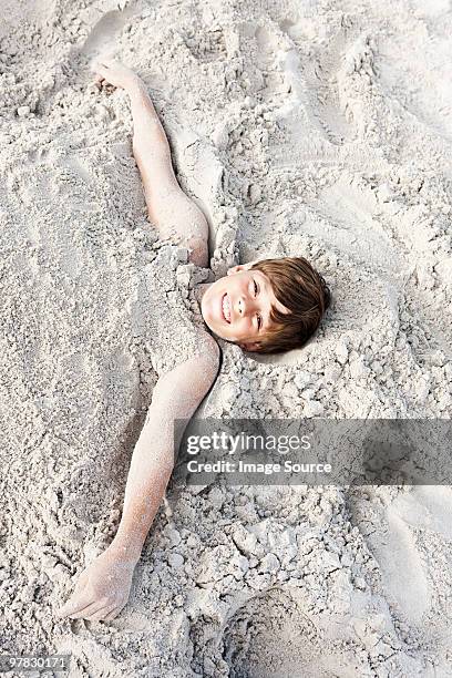 boy buried in sand - buried in sand stockfoto's en -beelden