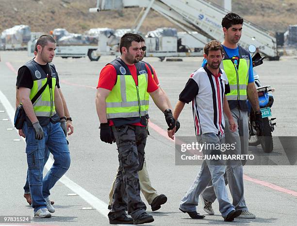 Spanish police officers take a group of Spanish detainees accused of drug trafficking to board an aircraft on their way back to Spain, at La Guaira...