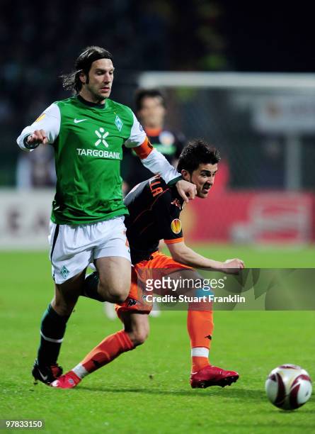 Torsten Frings of Bremen is challenged by David Villa of Valencia during the UEFA Europa League round of 16 second leg match between SV Werder Bremen...