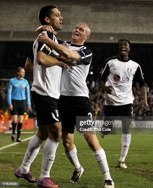 Clint Dempsey of Fulham celebrates scoring with Paul Konchesky and Dickson Etuhu during the UEFA Europa League Round of 16 second leg match between...