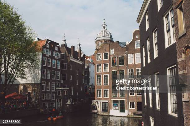 buildings by canal against sky in city - bortes stockfoto's en -beelden