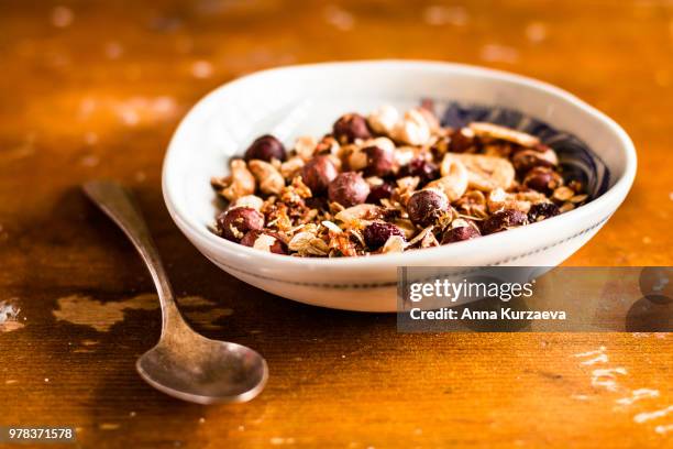 championship game of granola or muesli with toasted oat flakes, banana chips, cashew nuts, hazelnuts on a wooden table, selective focus. food for breakfast or snack. healthy and organic food. - raisin bran stock pictures, royalty-free photos & images