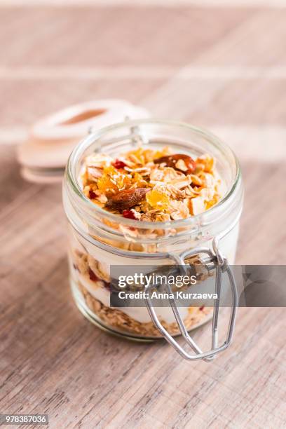 traditional breakfast from switzerland. jar of homemade muesli bircher with plain yogurt, toasted oat flakes, almonds, peanuts, dried fruits and honey on a wooden table, selective focus. organic food. - raisin bran stock pictures, royalty-free photos & images