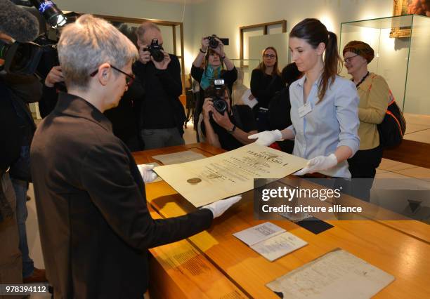 April 2018, Germany, Trier: Surrounded by journalists, curator Barbara Wagner and restorator Sarah Bruch place the doctoral certificate of Karl Marx...