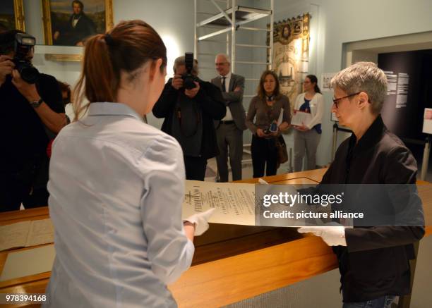 April 2018, Germany, Trier: Curator Barbara Wagner and restorator Sarah Bruch place the doctoral certificate of Karl Marx on the exhibition table at...