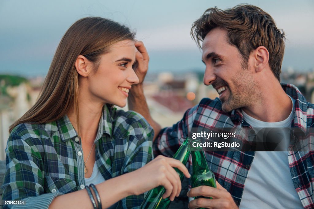 Young couple looking at each other while having celebratory toast on the roof
