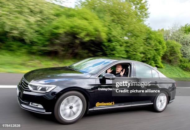 April 2018, Germany, Hanover: Test engineer Dennis Scholl driving on the A2 motorway and holding up his hands inside a "Cruising Chauffeur" car...