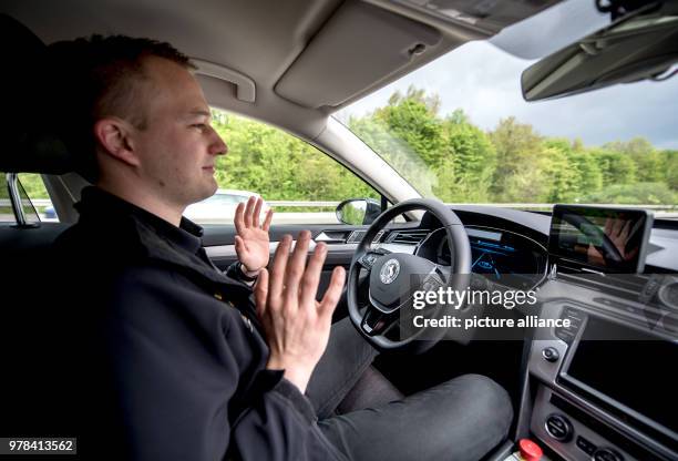 April 2018, Germany, Hanover: Test engineer Dennis Scholl driving on the A2 motorway and holding up his hands inside a "Cruising Chauffeur" car...
