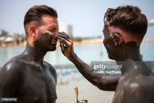 Tourists cover themselves in mud from the Dead Sea in Israel on June 17, 2018. The Dead Sea is a popular travel destination and lies 422 meters below...