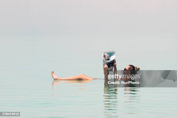 Tourist poses for a picture while floating in the Dead Sea in Israel on June 17, 2018. The Dead Sea is a popular travel destination and lies 422...