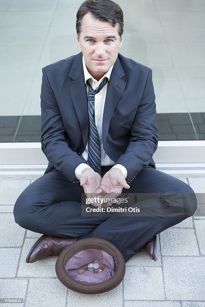 Businessman begging on pavement