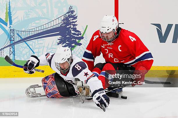 Greg Shaw of the United States battles for the puck against Tommy Rovelstad of Norway during the second period of the Ice Sledge Hockey Play-off...