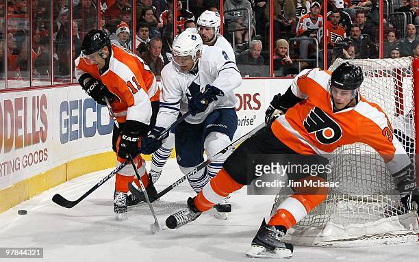 Luke Schenn of the Toronto Maple Leafs skates against Blair Betts and Darroll Powe of the Philadelphia Flyers on March 7, 2010 at Wachovia Center in...