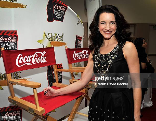 Actress Kristen Davis signs a director's chair for a charity auction for Coca-Cola before the ShoWest final night banquet and awards ceremony at...