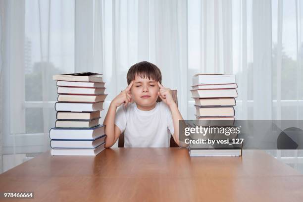 boy, 8-9 years, trying to concentrate surrounded by stacks of books - boys only caucasian ethnicity 6 7 years stock pictures, royalty-free photos & images