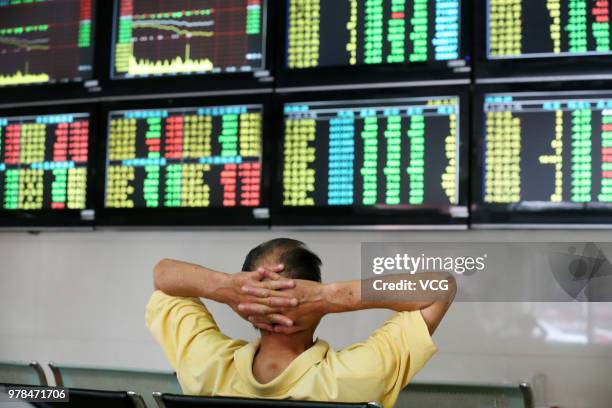 An investor watches the electronic board at a stock exchange hall on June 19, 2018 in Nantong, China. Chinese shares plunged on Tuesday with the...