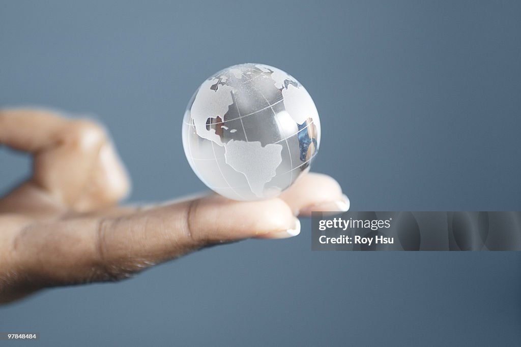 Crystal globe balanced on fingertip