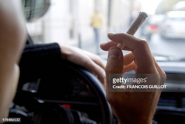 Une personne fume une cigarette de cannabis, le 08 octobre 2002 à Paris, alors qu'elle se trouve au volant d'un véhicule. L'Assemblée nationale a...