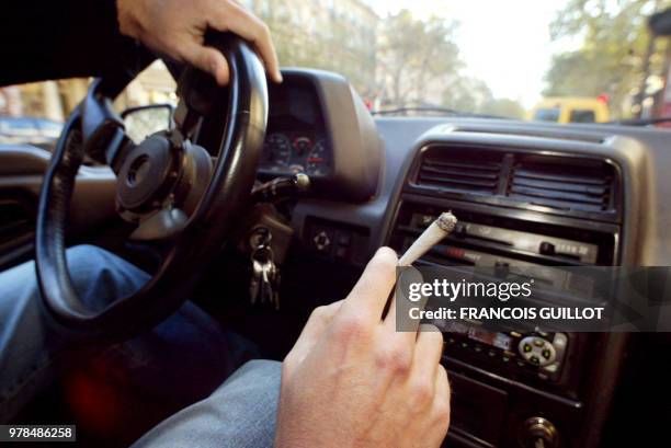 Une personne fume une cigarette de cannabis, le 08 octobre 2002 à Paris, alors qu'elle se trouve au volant d'un véhicule. L'Assemblée nationale a...