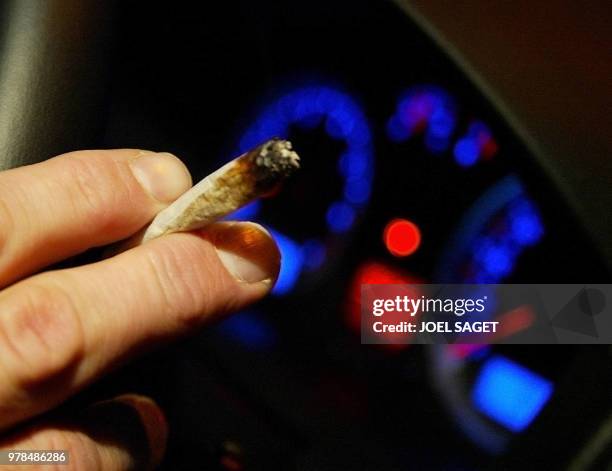 Un automobiliste s'allume un joint, le 10 octobre 2002 à Zolder. Le rapport sur la proposition de loi visant à sanctionner la drogue au volant a été...