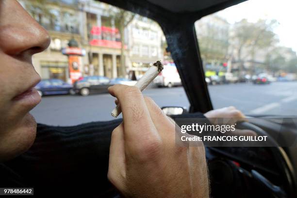 Une personne fume une cigarette de cannabis, le 08 octobre 2002 à Paris, alors qu'elle se trouve au volant d'un véhicule. L'Assemblée nationale a...