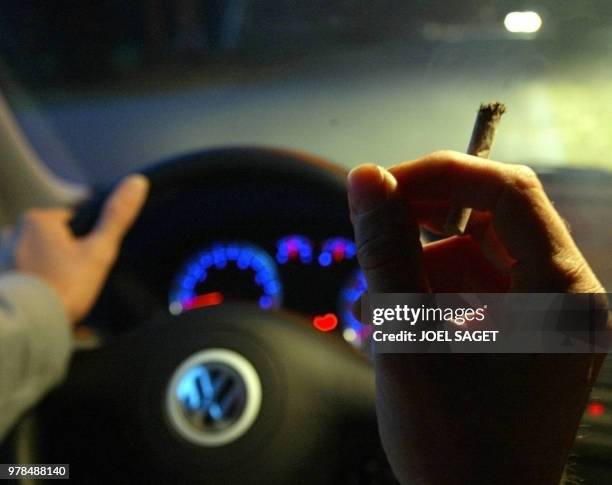 Un automobiliste s'allume un joint, le 10 octobre 2002 à Zolder. Le rapport sur la proposition de loi visant à sanctionner la drogue au volant a été...