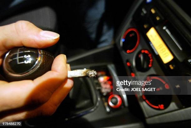 Un automobiliste s'allume un joint, le 10 octobre 2002 à Zolder. Le rapport sur la proposition de loi visant à sanctionner la drogue au volant a été...
