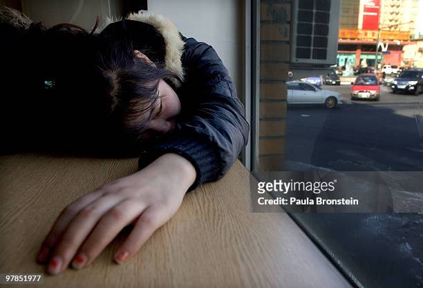 Nandia a street kid, passes out on the table at a restaurant after sleeping in a stairwell the night before on March 12, 2010 in Ulaan Baatar,...