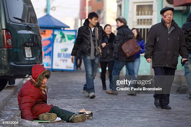 Otgonjargal sits on the icy cold street singing to get some quick cash on March 16, 2010 in Ulaan Baatar, Mongolia. Otgonjargal spends her time on...