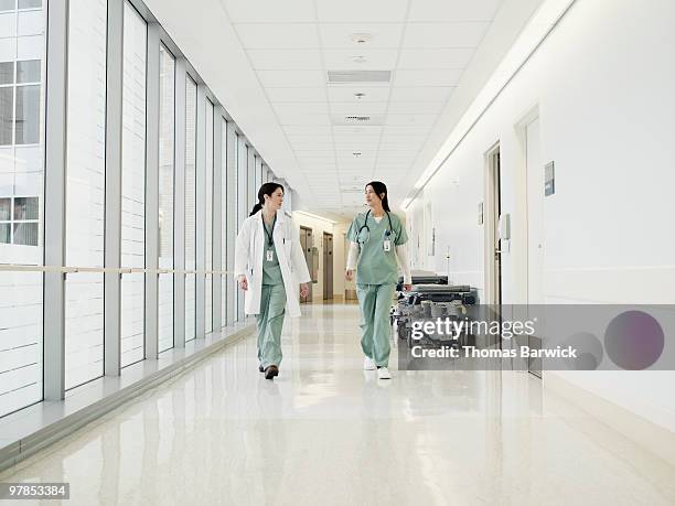 two doctors in discussion walking down corridor - corridor bildbanksfoton och bilder