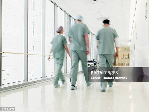 surgical team walking through hospital corridor - korridor stock-fotos und bilder