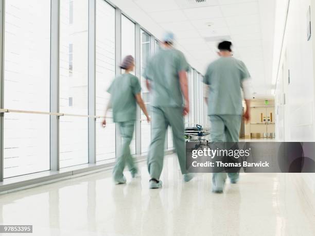 surgical team walking through hospital corridor - corridoio caratteristica di una costruzione foto e immagini stock