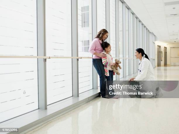 surgeon kneeling down to talk to young girl - child standing talking stockfoto's en -beelden