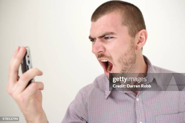 young man shouting at mobile telephone - three quarter front view stock pictures, royalty-free photos & images