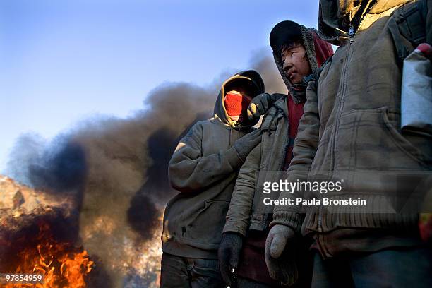 Mongolian boys ages 12-14 warm up next to a fire at the garbage dump where they work March 16, 2010 in Ulaan Baatar, Mongolia. Mongolia suffers with...