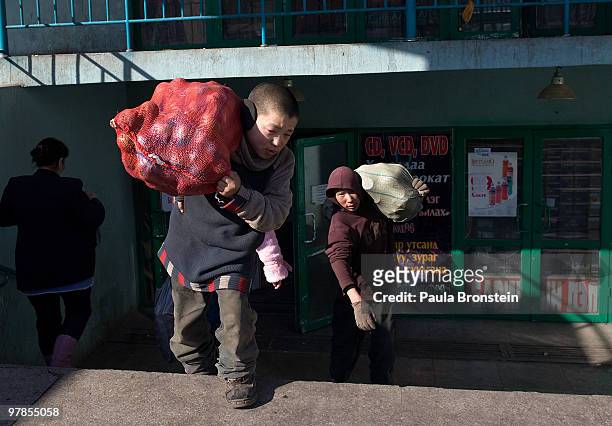 Year old Mongolian boy works in the market carries a heavy bag March 16, 2010 in Ulaan Baatar, Mongolia. Mongolia suffers with a very high number of...