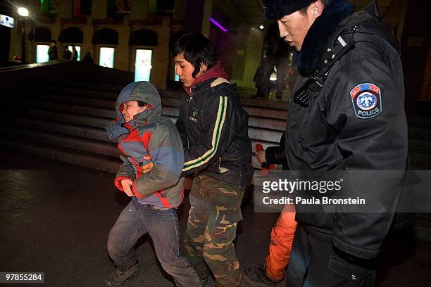 Mongolian police observe as an older boy helps to round up street kids as they round up the young boys getting them out of the cold March 11, 2010 in...