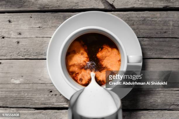 pouring milk into coffee cup - coffee milk stockfoto's en -beelden