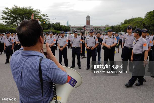 Taiwanese military veteran uses a megaphone in front of a line of policemen as demonstrators protest outside parliament building against a pension...