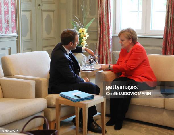 French President Emmanuel Macron serves some coffee to German Chancellor Angela Merkel before holding bilateral talks on June 19 at the Meseberg...