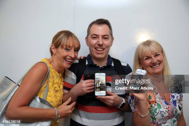 Fans show off their photographs after posing with Andy Murray during Day 2 of the Fever-Tree Championships at Queens Club on June 19, 2018 in London,...