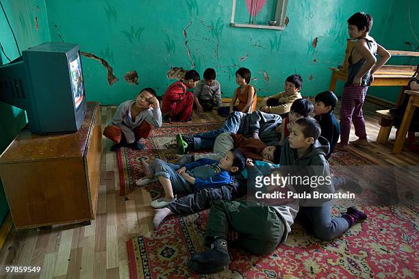Mongolian street children watch TV at a child detention center March 11, 2010 in Ulaan Baatar, Mongolia. The police picked up a dozen boys to get...