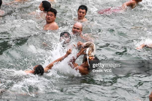People compete for a duck in the river to celebrate the Dragon Boat Festival at Fenghuang Ancient Town on June 18, 2018 in Fenghuang, China. The...