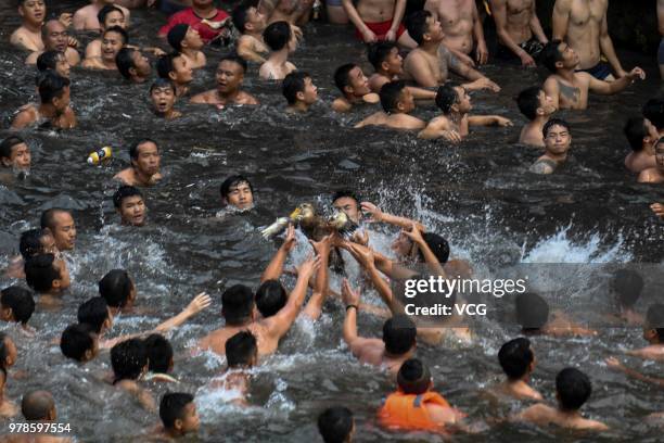 People compete for a duck in the river to celebrate the Dragon Boat Festival at Fenghuang Ancient Town on June 18, 2018 in Fenghuang, China. The...