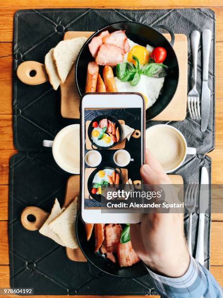 personal perspective view of a young man taking picture with smart phone of a cafe table with breakfast served in skillets - personal perspective or pov stock-fotos und bilder