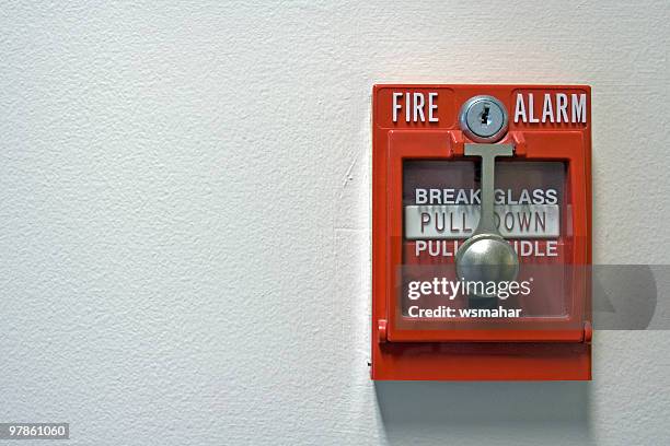 an isolated red fire alarm on a wall - sirene stockfoto's en -beelden