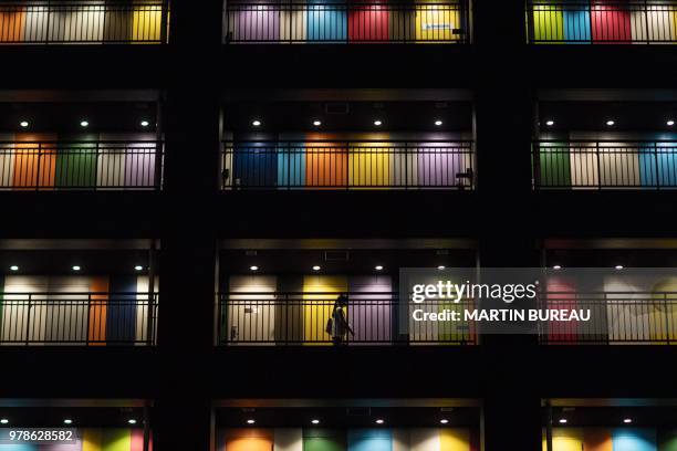 Woman walks along a passageway past appartements at a building in Tokyo on June 19, 2018.