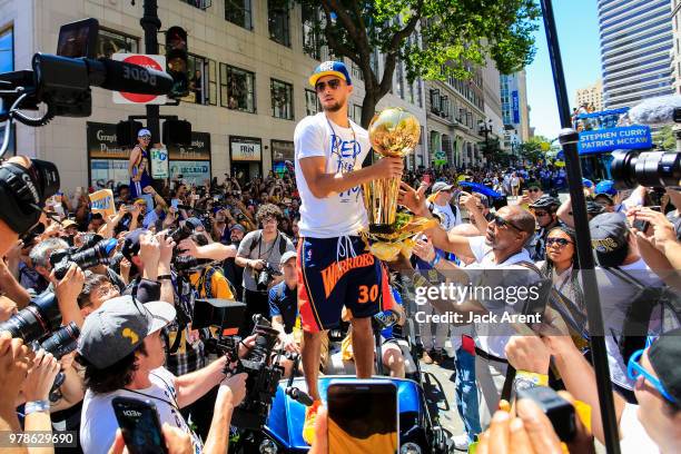 Stephen Curry of the Golden State Warriors holds up the Larry O'Brien Championship Trophy with fans during the Victory Parade on June 12, 2018 in...